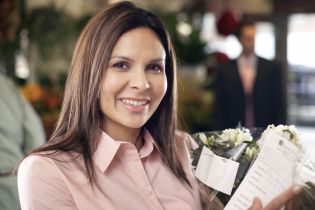 kwiaciarnia - kobieta trzyma kwiaty przygotowane do wysyłki